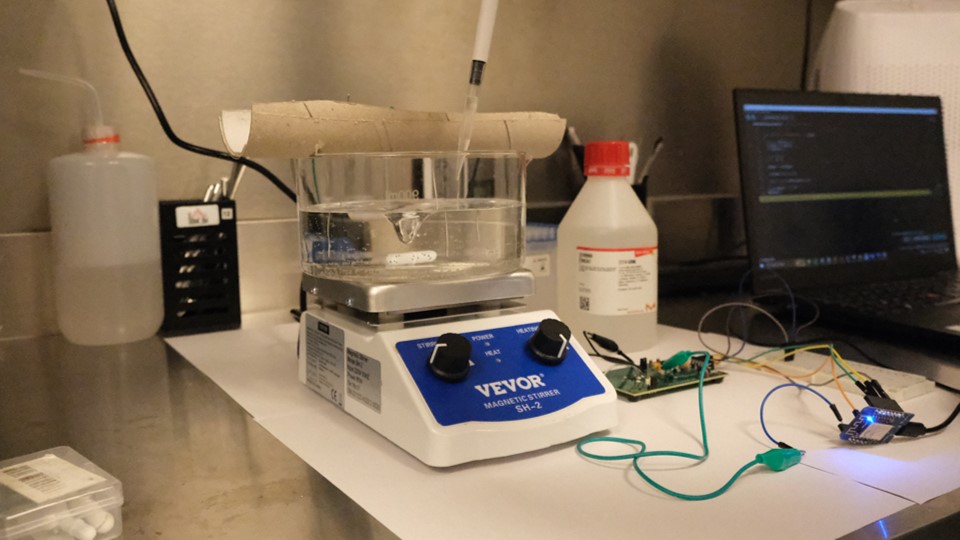 Experiment bench with stirrer, reagents and a laptop